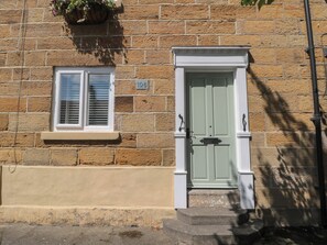 Ein Steinhaus mit einer grünen Tür und einem Fenster mit Fensterläden.