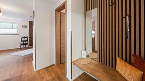 A modern interior with a wooden bench, a mirror, and a striped wall.