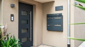 A modern building entrance with a dark door, a mailbox, and a sign indicating the address.
