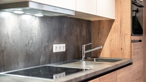 A modern kitchen with a stainless steel sink, wooden cabinets, and a built-in oven.