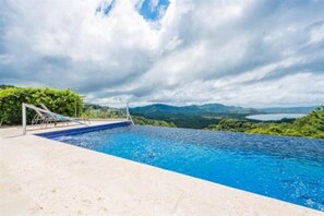 A swimming pool with a view of mountains and a cloudy sky.
