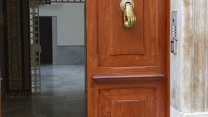 A wooden door with a brass handle, leading to a hallway with patterned tiles and an ornate archway. - Estudio Amor BRUJO by Cadiz4Rentals (Cádiz)