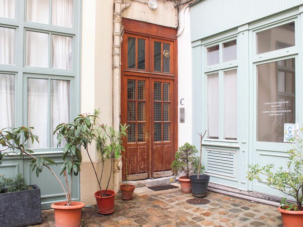 A building with a wooden door, potted plants, and a sign with names.