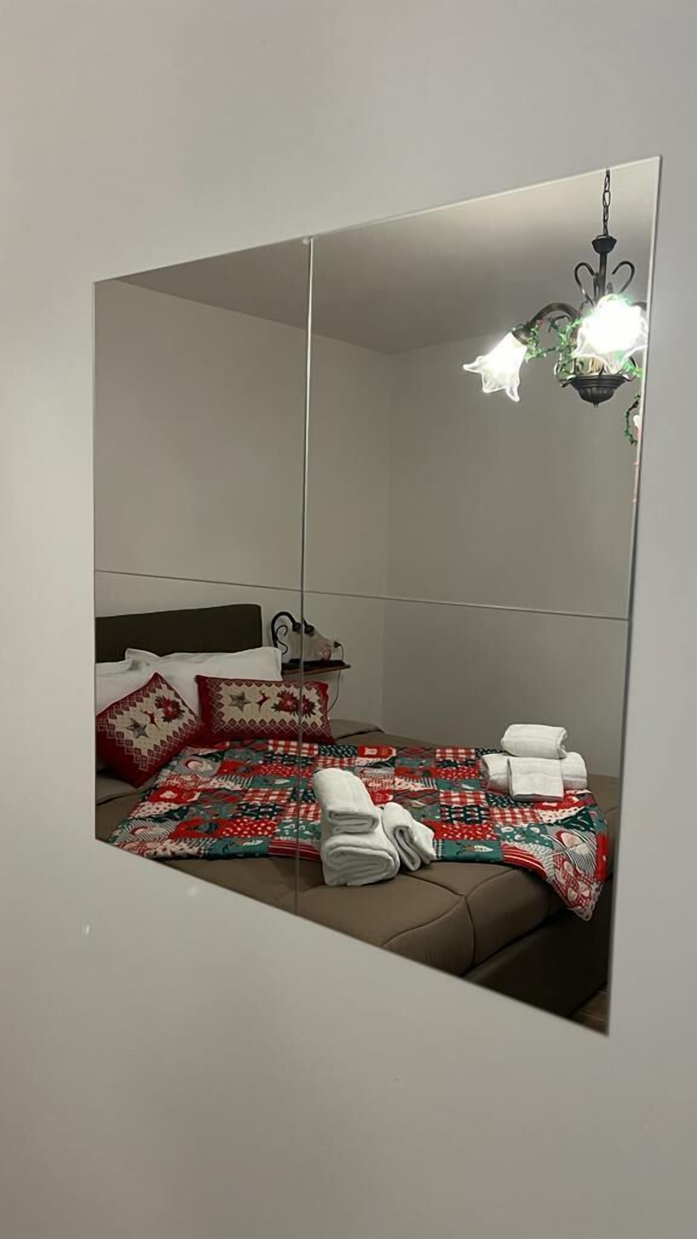 Ein Hotelzimmer mit einem großen Spiegel, einem Bett mit gemusterten Betttextilien, einem Nachttisch mit Lampe und einer Hängelampe.