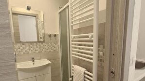 A bathroom with a sink, mirror, and glass shower door. - Il Campanile (Santa Maria del Molise)