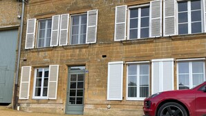 A two-story brick building with white shutters on the windows and a green door. - The Adelaide Boudoir, Charmant gîte avec lit king size et accès PMR (Vendresse)
