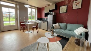 A modern kitchen with a dining area, a sofa, and a coffee table. - The Adelaide Boudoir, Charmant gîte avec lit king size et accès PMR (Vendresse)