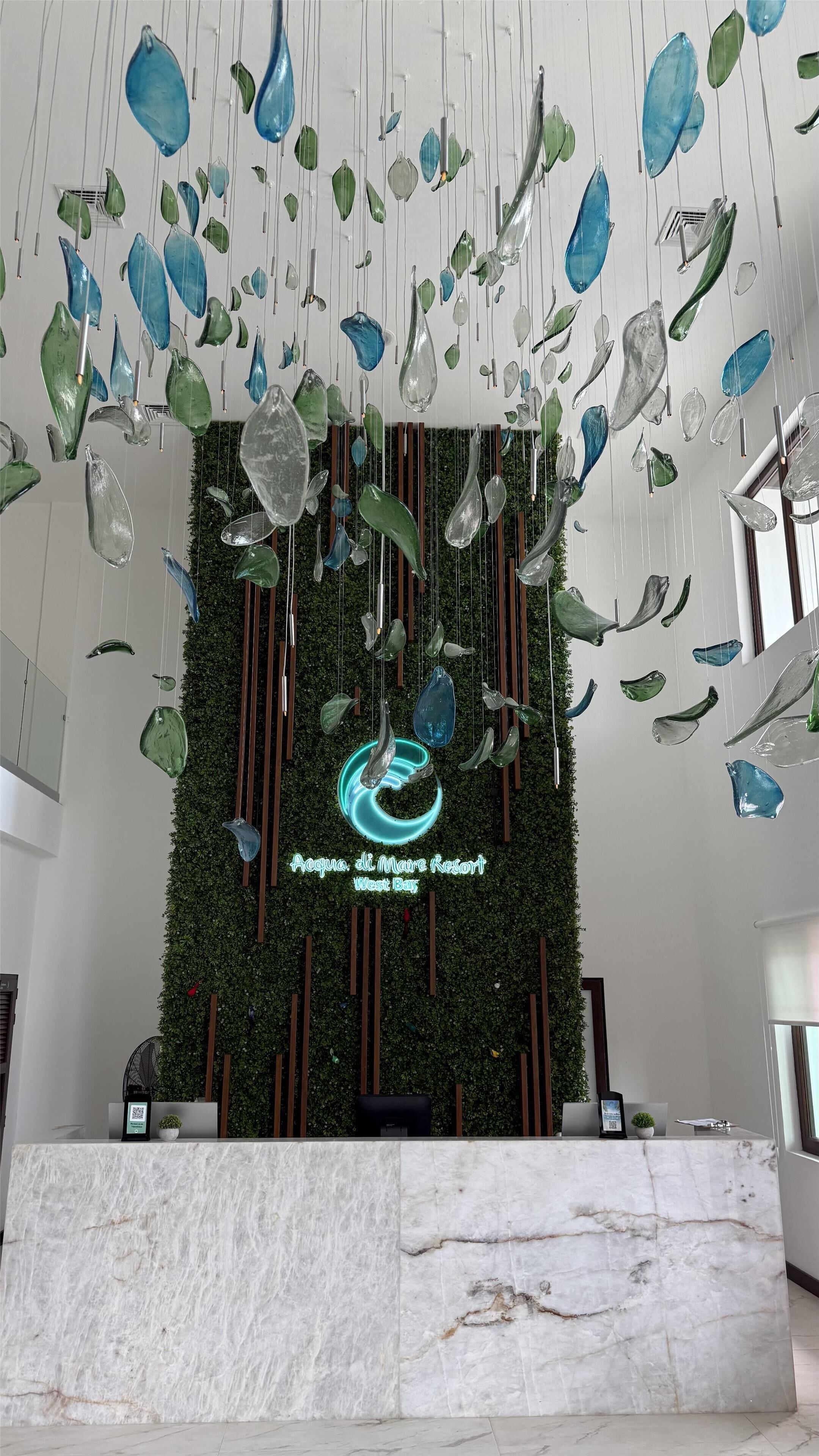 A reception area with a marble counter, hanging glass art, and a green wall with a logo.