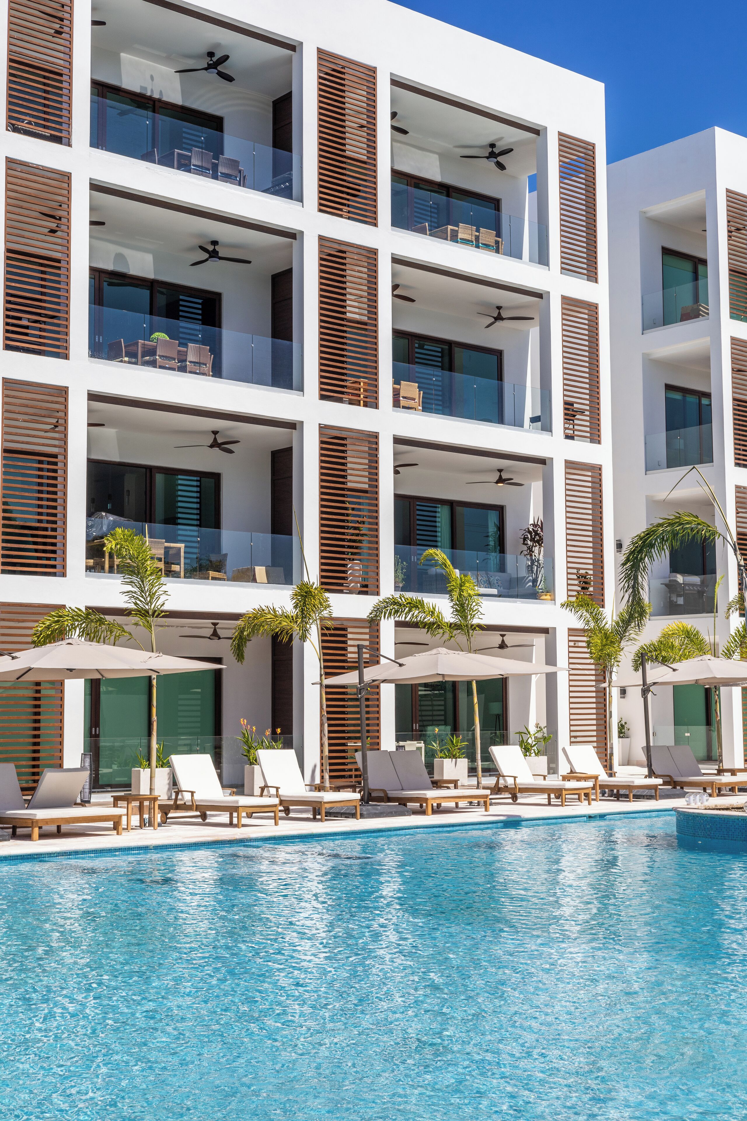 Un hôtel moderne doté de nombreux balcons, d’une piscine et de chaises longues.