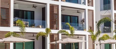 Un hôtel moderne doté de nombreux balcons, d’une piscine et de chaises longues.