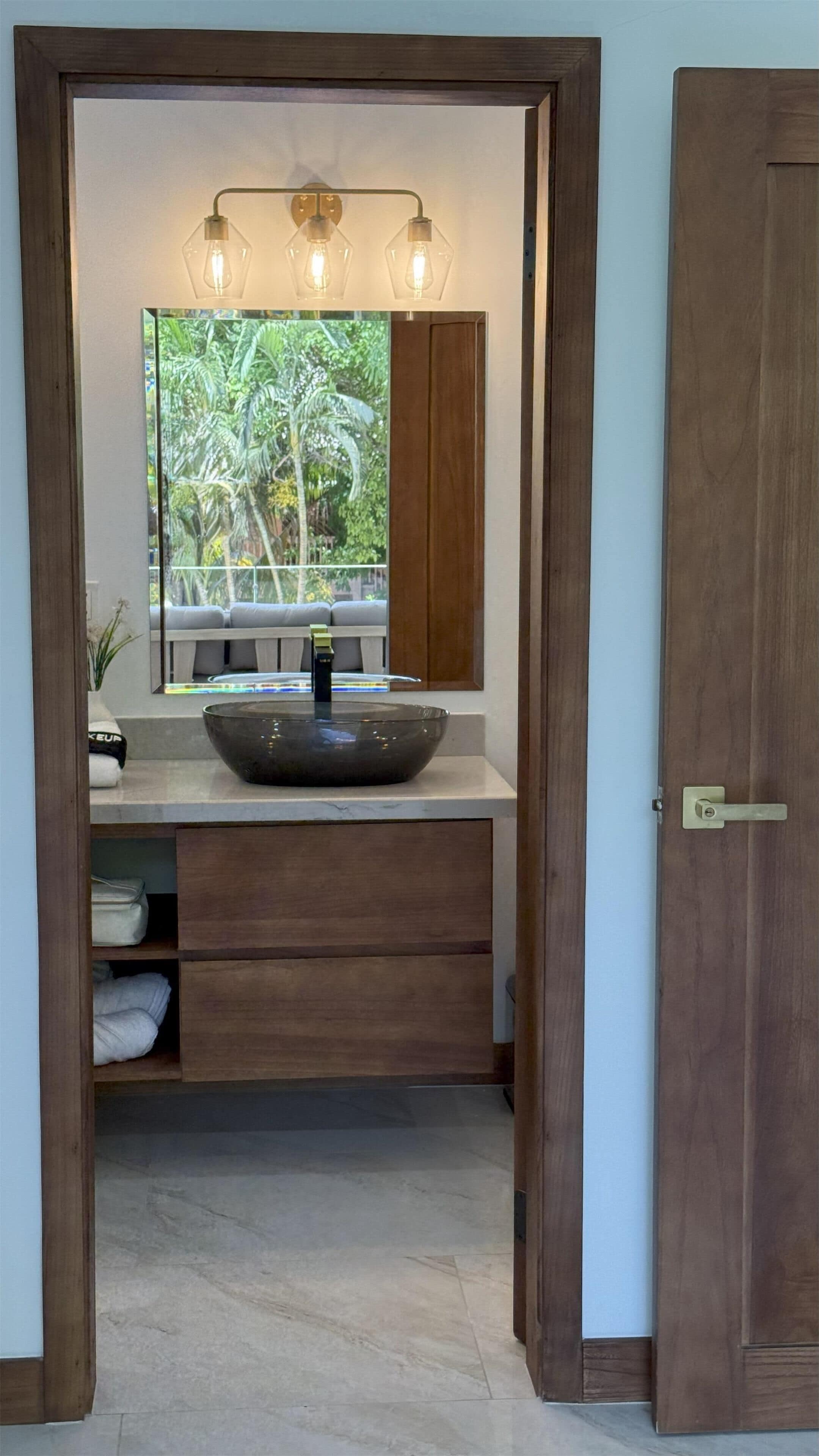 A bathroom with a wooden vanity, a large mirror, and a bowl sink.