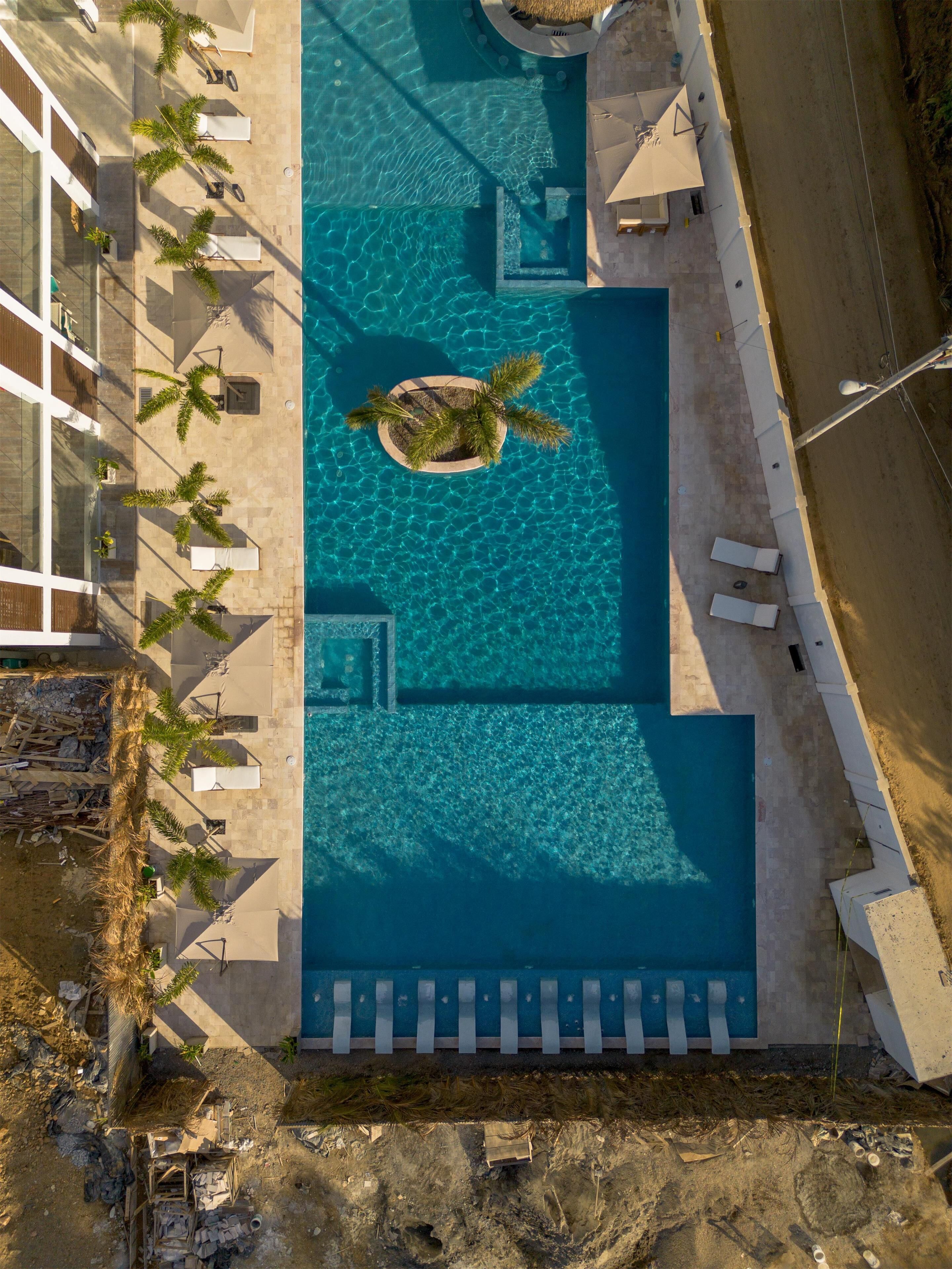 Una piscina al aire libre, sombrillas, sillones reclinables de piscina