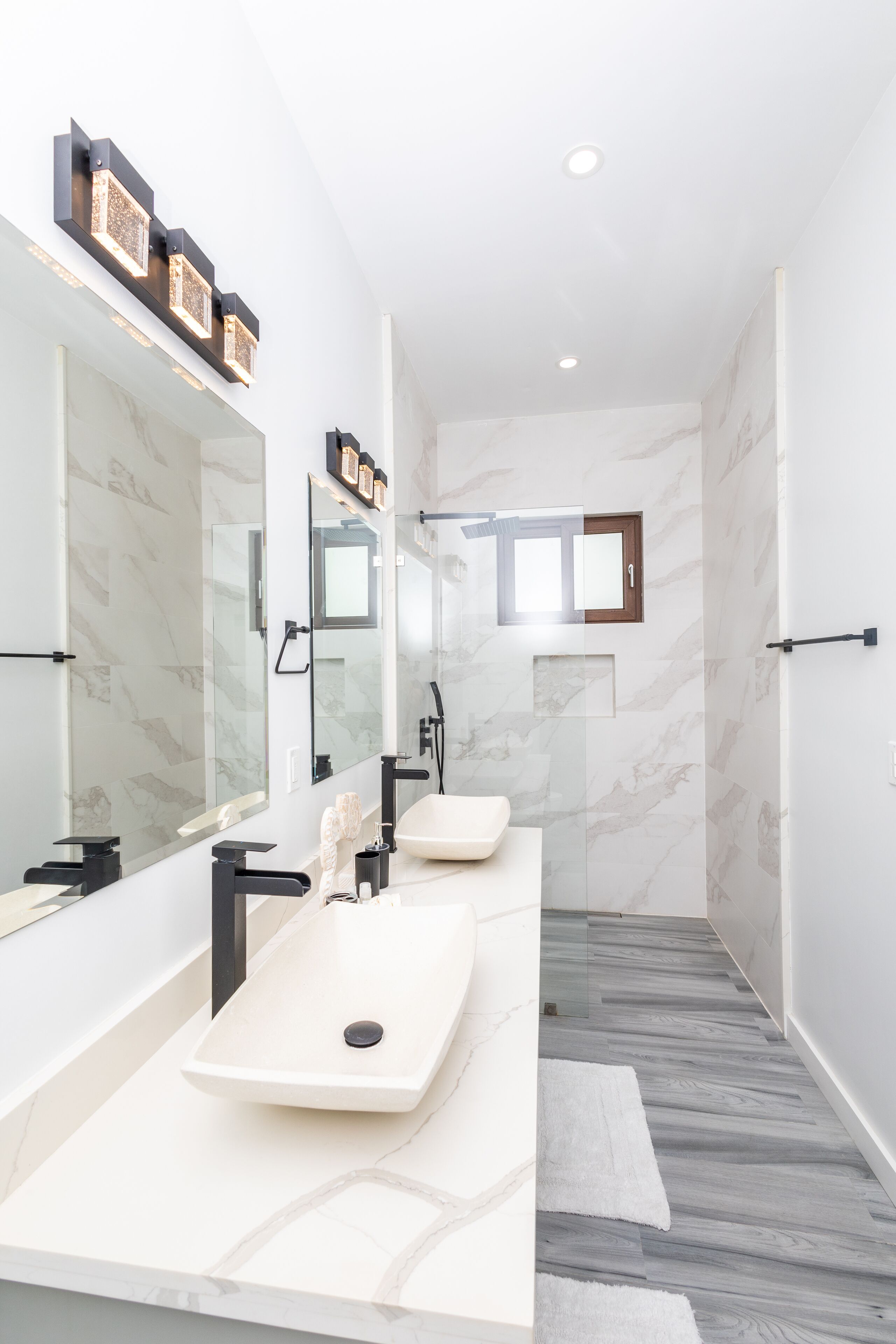 Un baño moderno con dos lavamanos, un espejo grande y una zona de ducha.