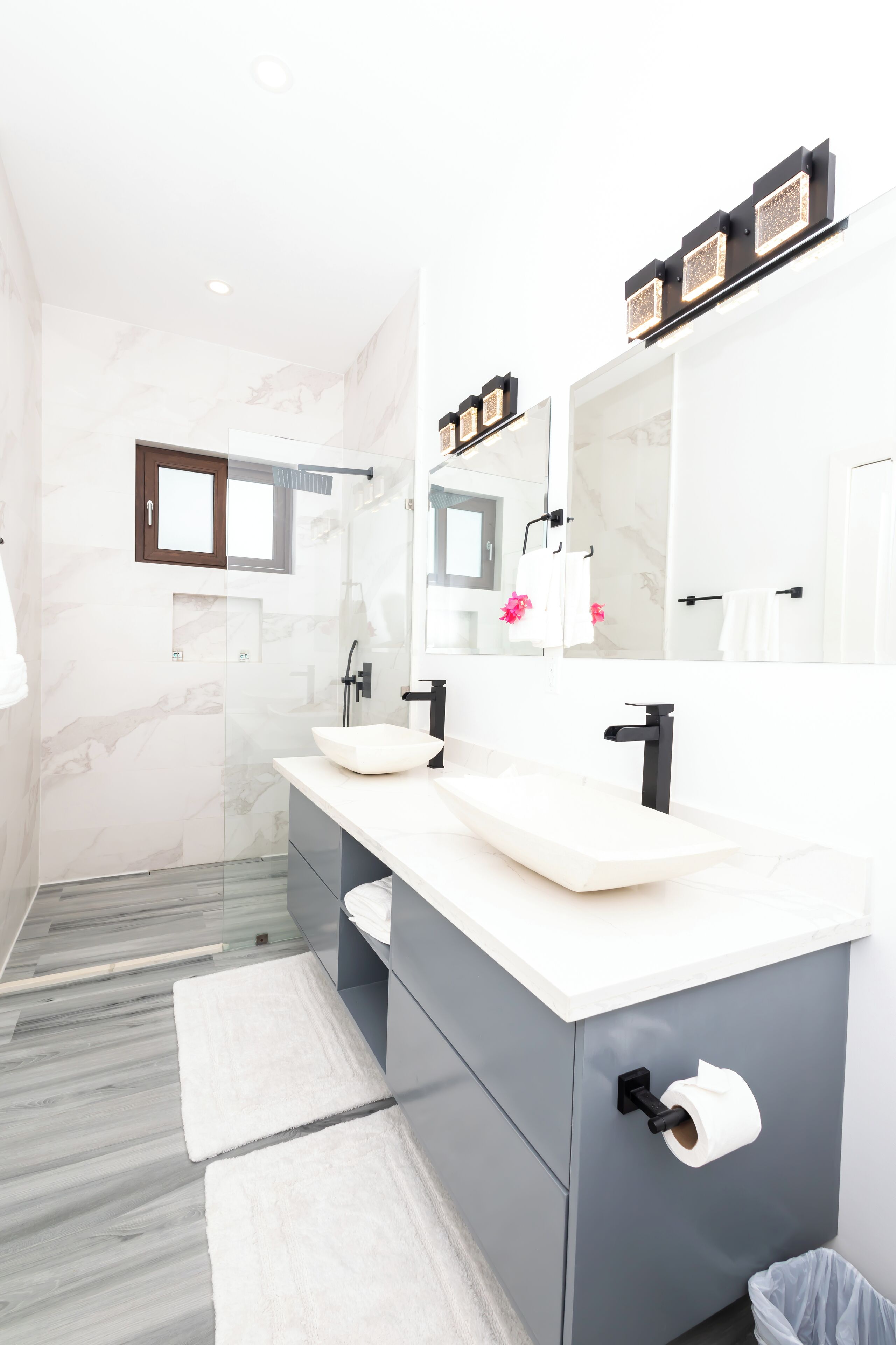 A modern bathroom with two sinks, a large mirror, and a shower area.