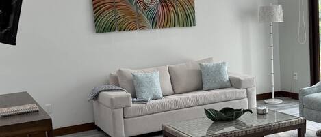 A modern living room with a sofa, coffee table, and artwork on the wall.