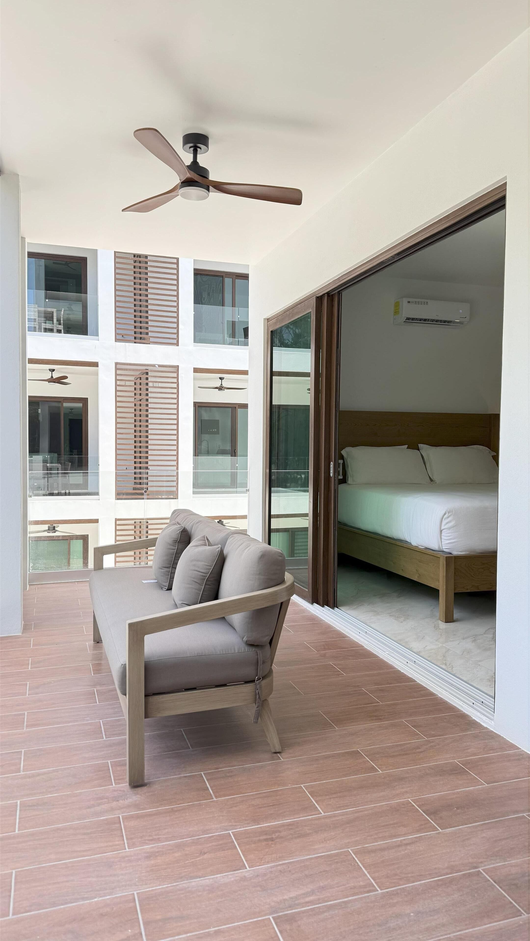 A modern room with a sofa, a ceiling fan, and a bed with a wooden headboard.