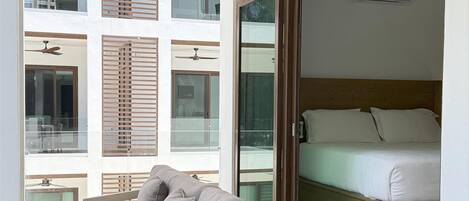 A modern room with a sofa, a ceiling fan, and a bed with a wooden headboard.