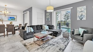 Una sala moderna con un sofá modular, una mesa de centro y un comedor con sillas y una mesa.