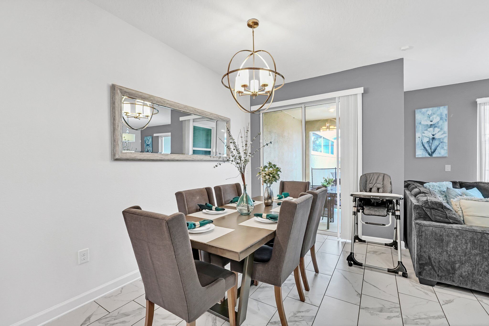 A modern dining area with a large table, chairs, and a chandelier.