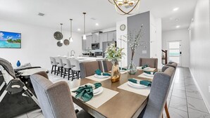 Un comedor moderno con una mesa larga, sillas y una araña.