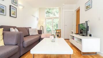 Una sala de estar moderna con un sofá, una mesa de centro y un televisor sobre un mueble.