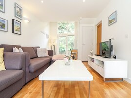 Una sala de estar moderna con un sofá, una mesa de centro y un televisor sobre un mueble.