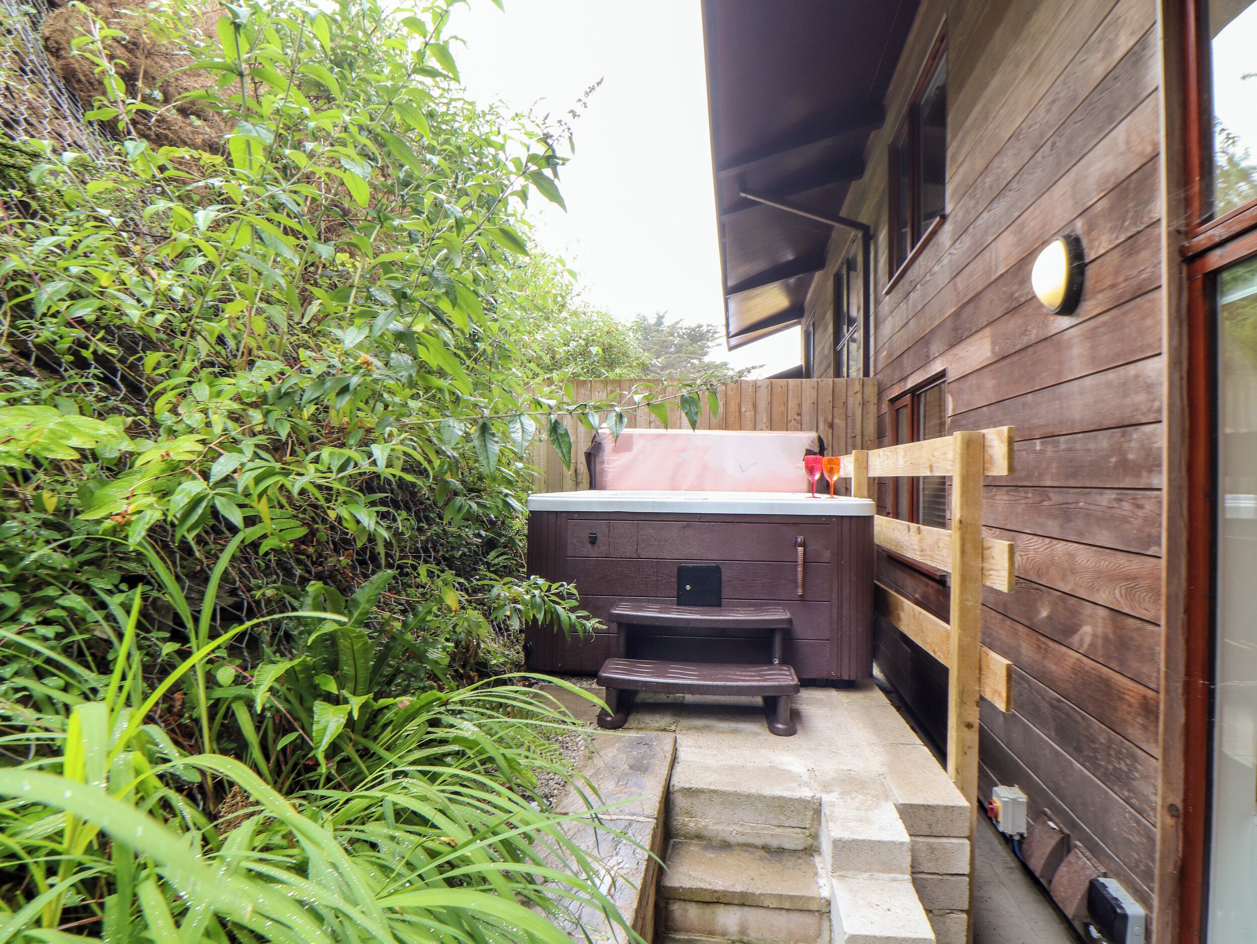 A wooden building with a hot tub and a wooden deck.
