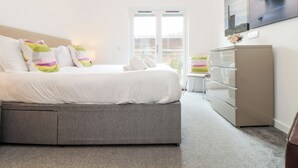 A bedroom with a bed, dresser, and a view through a glass door. - Garras (Truro)