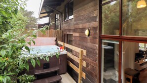 A wooden cabin with a hot tub, wooden deck, and large windows. - Garras (Truro)