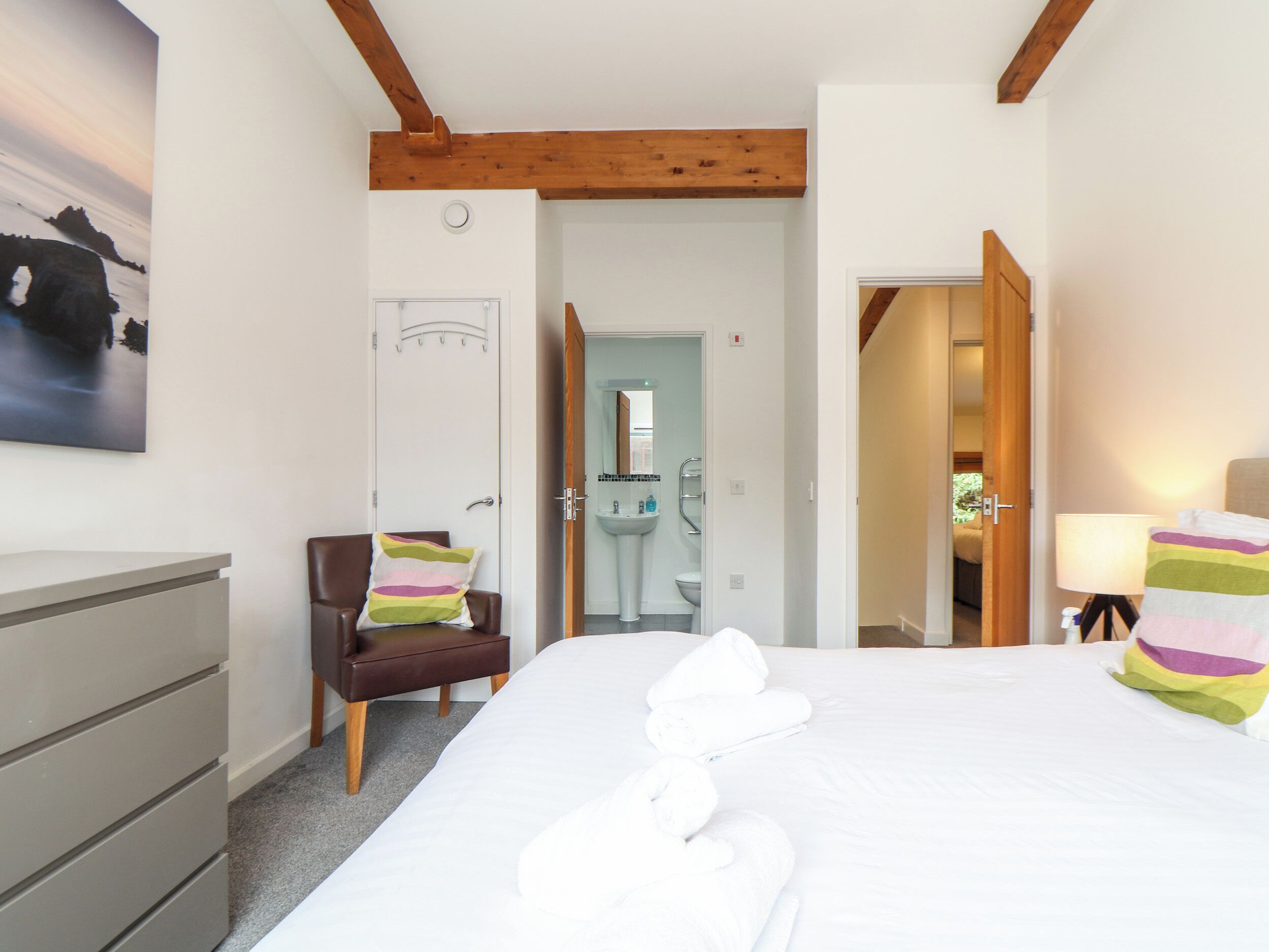 Habitación de hotel con cama, una silla, escritorio y baño, con vista al mar.
