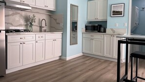 Una cucina moderna con mobili bianchi, una cappa in acciaio inossidabile, un forno a microonde e un lavello con rubinetto.
