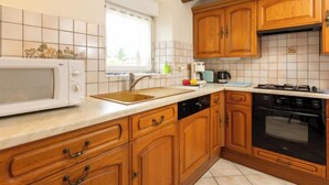 A kitchen with wooden cabinets, a microwave, a sink, and a stove. - Emeraude by Interhome (Saint Coulomb)
