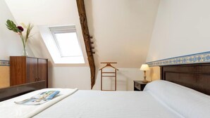 A bedroom with a large bed, a wooden wardrobe, a small table with a lamp, a hanging rack, and a skylight. - Emeraude by Interhome (Saint Coulomb)