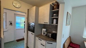 A compact kitchen with a built-in oven, a coffee maker, and a toaster.