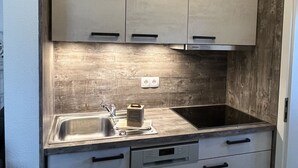 A compact kitchen with a wooden backsplash, a double sink, and built-in cabinets.
