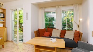 A cozy living room with a sofa, a wooden coffee table, and a bookshelf. - Im Kiefernweg DHH 21 by Interhome (Zinnowitz)