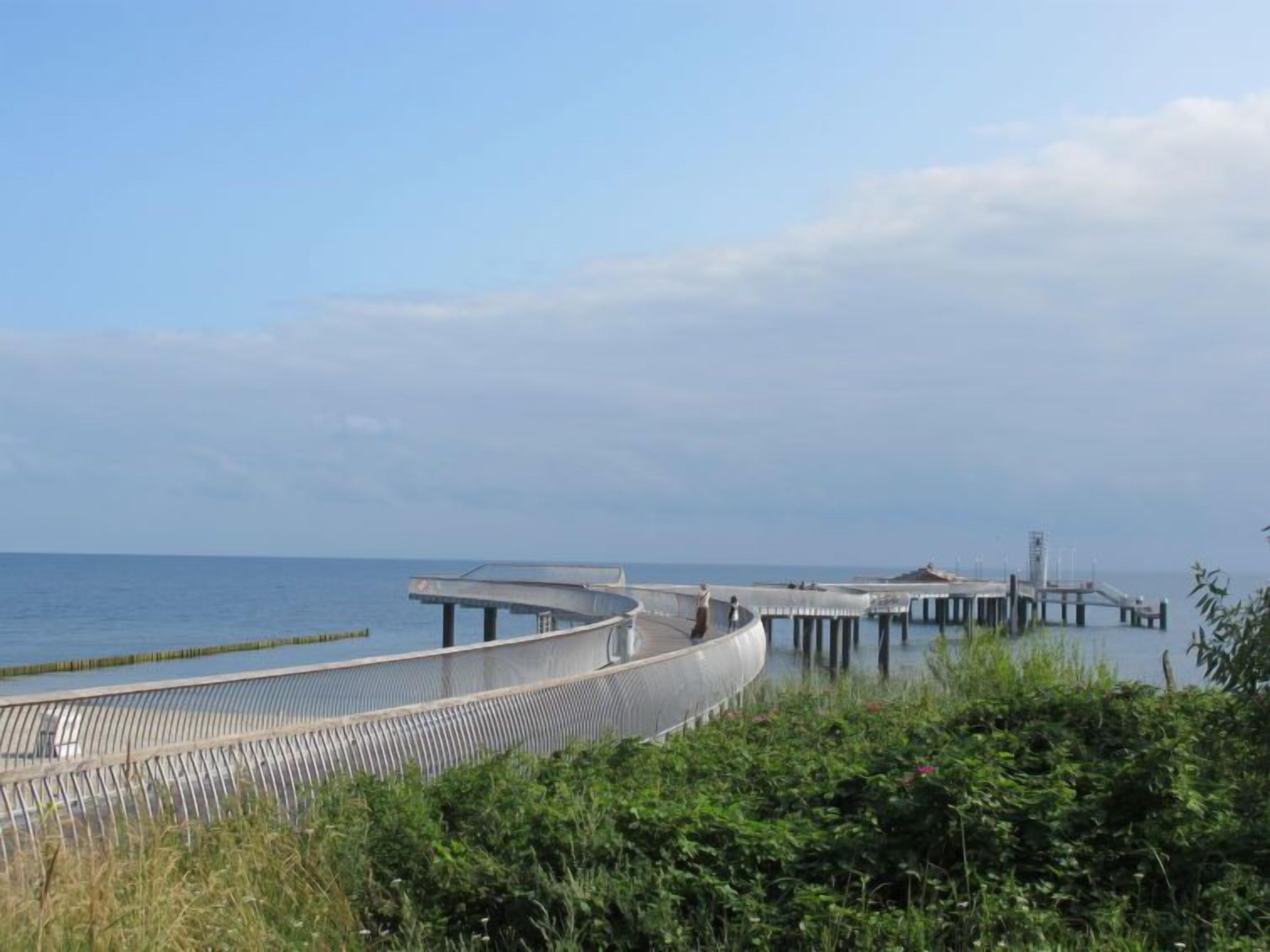 A coastal pier extending into the sea with a curved walkway.