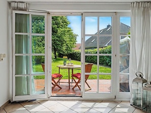 A room with a large sliding glass door leading to an outdoor patio with a table and chairs. - Achterwasser App.1 by Interhome (Zempin)