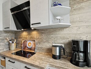 A modern kitchen with a built-in stove, a coffee maker, and a decorative coffee cup. - Achterwasser App.1 by Interhome (Zempin)