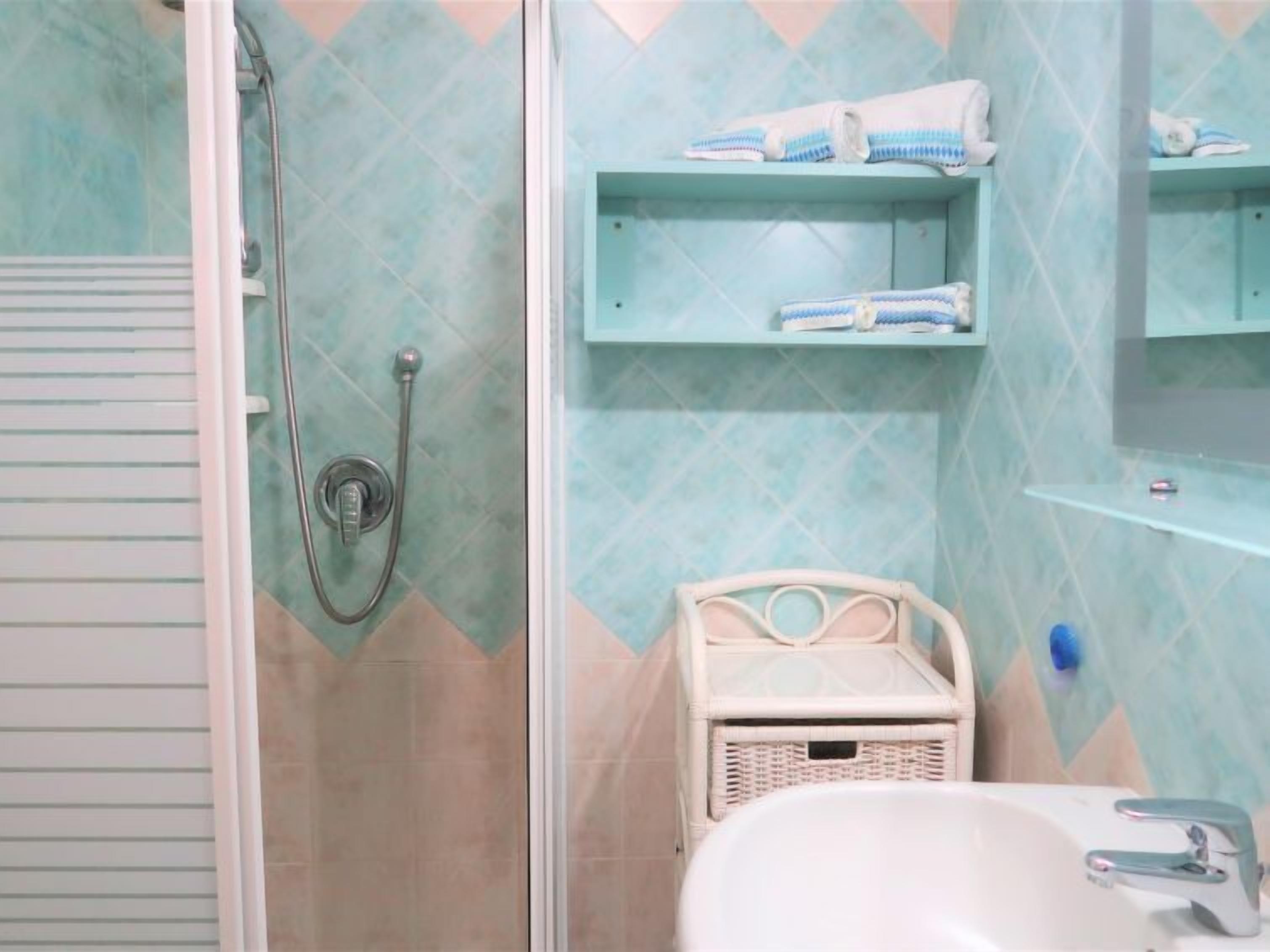 A bathroom with a shower, a sink, and a small wicker basket.
