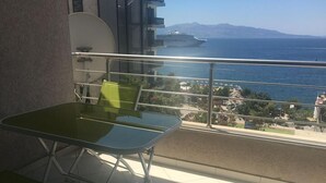 A balcony with a table and chairs, a view of the sea, and a cruise ship in the distance. - Appartamento in centro con vista e garage (Sarandë)