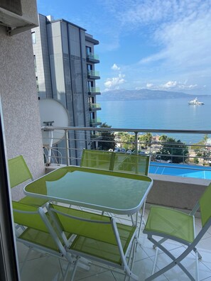Un balcon avec une table et des chaises, donnant sur une étendue d’eau et sur une chaîne de montagnes lointaine.