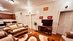 A living room with a sofa, a TV on a wooden stand, a fan, and a patterned rug. - Upper flat in Eccles Home, 3 bedrooms, sleeps 6, AC, Hot Water (Georgetown)