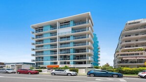 A multi-story modern building with balconies, a sign for 'AQUAVIEW', and several cars parked in front.