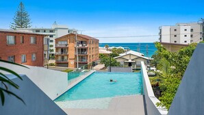 A pool area with a view of the ocean, surrounded by buildings.