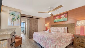 Ein Schlafzimmer mit Bett, Deckenventilator, Nachttisch, Lampe und einem Gemälde an der Wand.