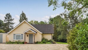 Een gelijkvloers huis met een beige gevel, een donker dak en een oprit met grind.