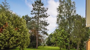 Een verzorgde tuin met verschillende bomen en een heldere lucht.
