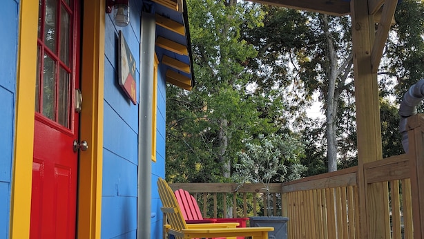 A wooden deck with a red door and a yellow chair. - Da Princess Inn - Walk to Downtown (Lafayette)