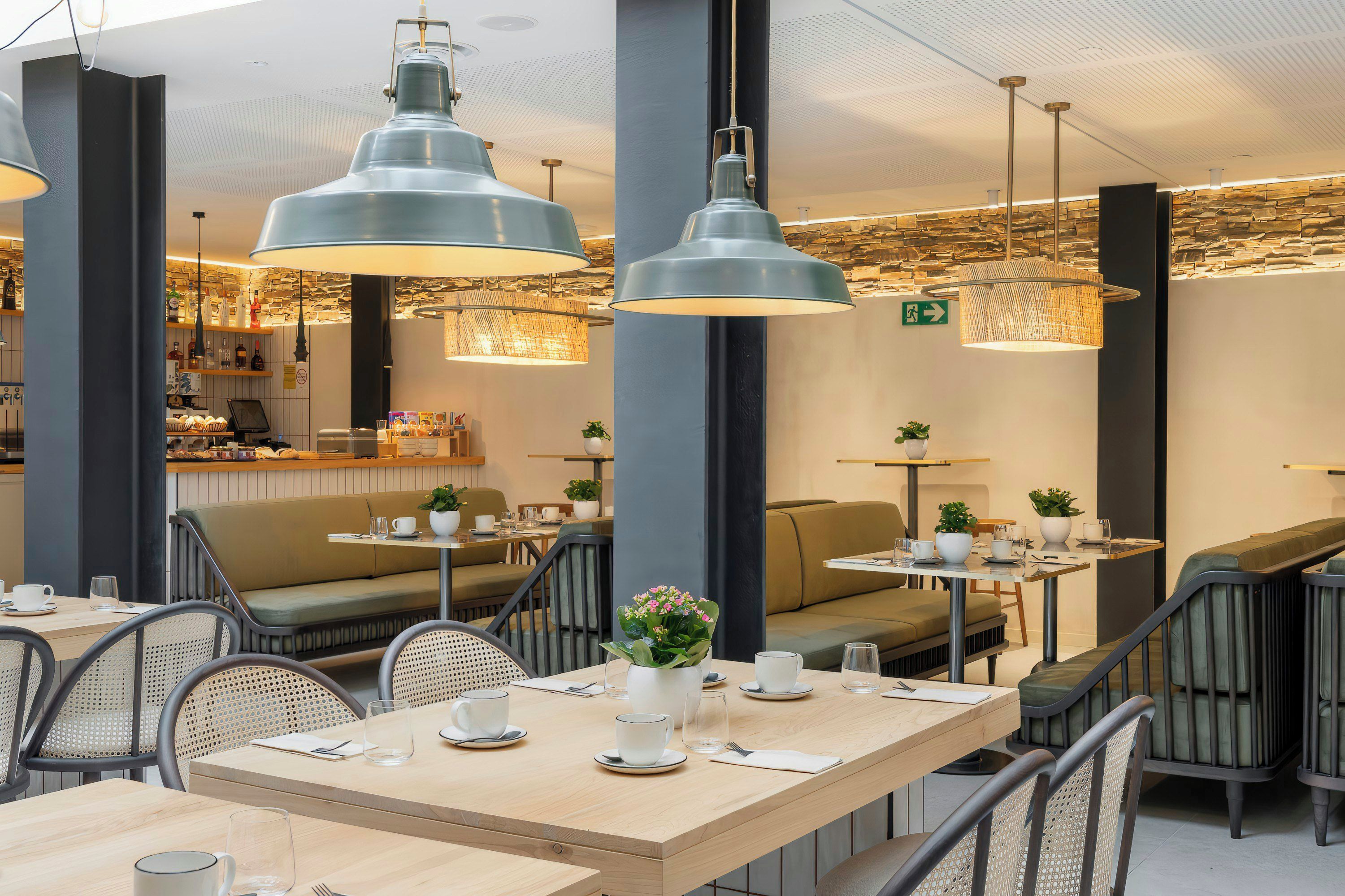 A modern cafe interior with high tables, chairs, and hanging pendant lights.